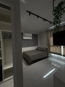 a bedroom with a bed and a flat screen tv at Studio 44 Luxo Design Com Closet, Office e Ar in Mogi das Cruzes