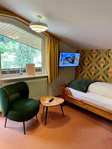 a bedroom with a bed and a chair and a window at Schwarzwaldhotel Klumpp in Baiersbronn
