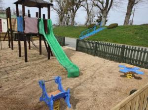 a playground with a green slide in the sand at Puy Rond Camping in Bressuire