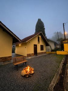 a bench sitting next to a fire in front of a house at Recanto da Neblina in Monte Verde