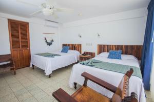 a hotel room with two beds and a chair at Hotel Rosita in Puerto Vallarta +43 photos