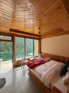 a bedroom with a large bed and a large window at Venky's Shoja in Jibhi