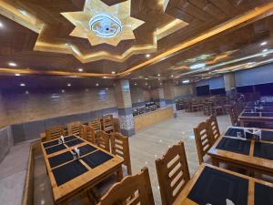 a restaurant with wooden tables and chairs and a chandelier at The Park Green Resorts in Manāli