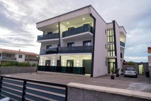 a white apartment building with a parking lot at Nejla Apartmani Stoj in Ulcinj