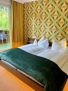 a bedroom with a large bed with a green blanket at Schwarzwaldhotel Klumpp in Baiersbronn +75 photos