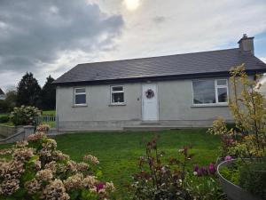 a gray house with a yard with flowers at Meadow View in Kilkenny