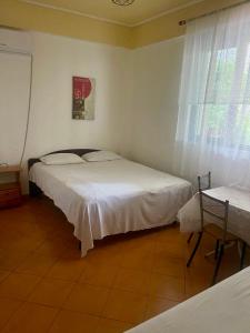 a bedroom with two beds and a table and window at Mani rooms in Durrës
