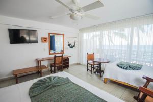 a bedroom with a bed and a desk and a table at Hotel Rosita in Puerto Vallarta