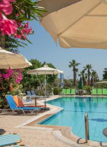 a swimming pool with chairs and umbrellas at Violetta Hotel in Amoudara Herakliou