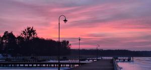 a pier with a street light and a sunset at Zielone Okno Apartament w Augustowie blisko jeziora i centrum in Augustów