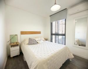 a bedroom with a white bed and a window at Departamento 1 dormitorio Edificio SnJ in Rosario