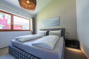 a bedroom with a bed with white sheets and a window at hus9 in Mittelberg