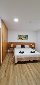 a bedroom with a large bed and wooden floors at Vivenda Do Relaxo '' Relax Villa " in Freiria +42 photos