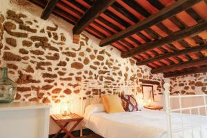 a bedroom with a bed and a stone wall at Masia Olivera in Sant Pau dʼOrdal
