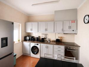 a kitchen with white cabinets and a washing machine at Apartamento Vicentino in Vila Nova de Milfontes