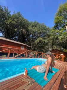 a woman laying on a blue towel next to a swimming pool at Cabañas Grazie in Oliveros