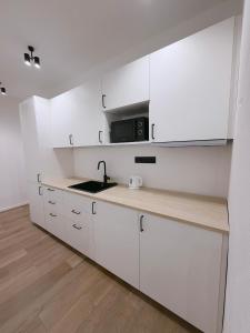 a white kitchen with a sink and a microwave at Milada 7 Suits in Brno