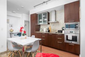 a kitchen with wooden cabinets and a white table and chairs at Downtown Toronto CN tower Condo in Toronto