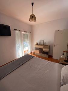 a bedroom with a bed and a tv and a window at Apartamento Vicentino in Vila Nova de Milfontes