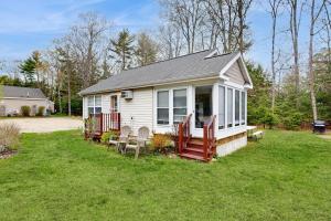 a small white house with a porch and chairs at Selkie Village in Wells