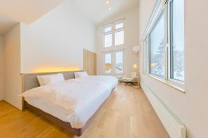 a bedroom with a large white bed and windows at Rose - Rusutsu Chalets in Kimobetsu