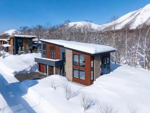 a home in the snow with mountains in the background at Rose - Rusutsu Chalets in Kimobetsu