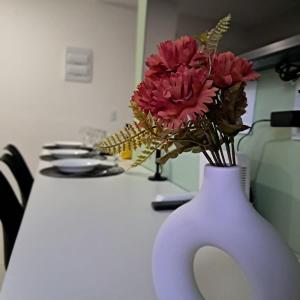 a white vase with flowers in it on a table at Apto com ar e piscina próximo a Cabo Frio e Arraial do Cabo in São Pedro da Aldeia +36 photos