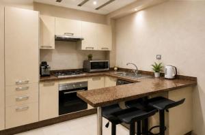 a kitchen with white cabinets and a counter with bar stools at Parc app in Mohammedia