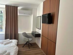 a bedroom with a bed and a tv and a chair at DION Hotel & Restaurant in Kumanovo