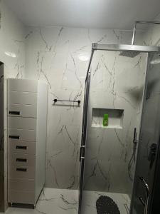 a bathroom with a shower with a marble wall at HomeByTheLake-Shiroke in Shirokë +35 photos