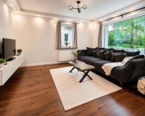 a living room with a black couch and a tv at Modernes Designer-Apartment in ruhiger Lage in Soltau +20 photos