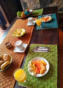 a table with plates of fruit and cups of orange juice at Hotel la Mana Nobsa in Nobsa