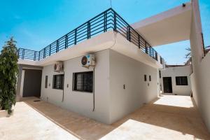 a white house with a staircase on top of it at Le Refuge, Residence Ibrahima in Rufisque
