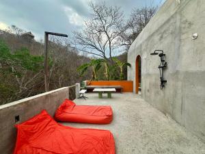 a patio with red pillows and a table and a bench at Casa Lai in Mazunte