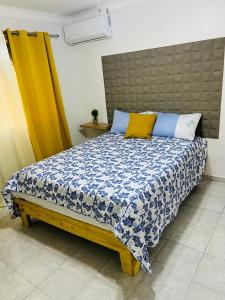 a bedroom with a bed with a blue and white comforter at Vacacional rent in Boca Chica