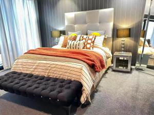 a bedroom with a large bed with a black bench at La Maison Barwon in Connewarre