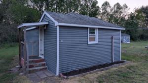 a small blue building with a staircase in a yard at Slumberland Motel Mount Holly in Mount Holly