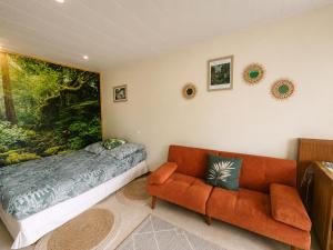 a bedroom with a bed and a couch in it at Appartement thème jungle in Avallon