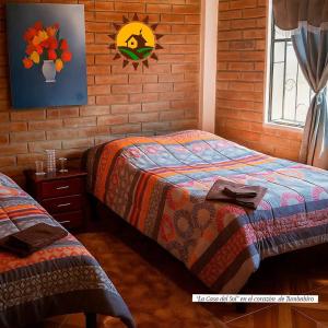a bedroom with two beds and a brick wall at Casa del Sol Tumbabiro in Tumbabiro