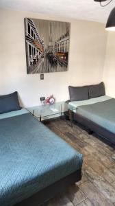 a room with two beds and a table and a painting at Estancia Familiar cerca de Paseo Durango in Durango
