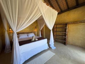 a bedroom with a canopy bed with curtains at Pousada Nitxi Awêry in Caraíva