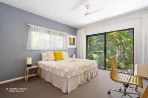 a bedroom with a bed and a window and a chair at Bessou in Charlotte Bay