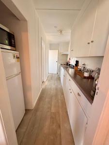 a kitchen with white cabinets and a wooden floor at Windy Garden in Marahau