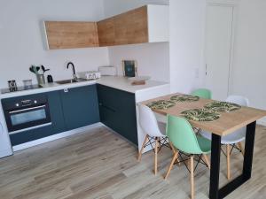 a kitchen with blue cabinets and a wooden table and chairs at appartement F2 in Ferrel
