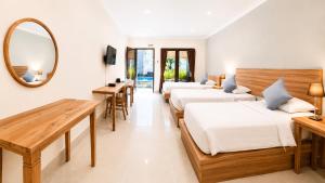 a bedroom with three beds and a mirror and tables at Radha Bali Hotel in Kuta +78 photos