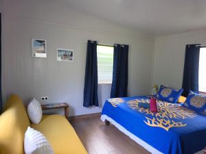 a bedroom with a bed and a yellow couch at Bora Bora Vairupe lodge in Bora Bora