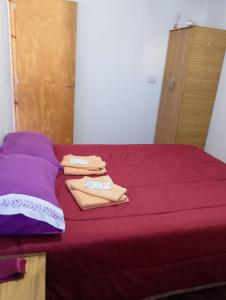 a bed with purple sheets and towels on it at LUCI Hospedaje in Uspallata
