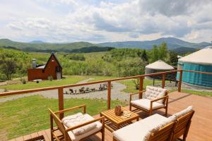 a deck with chairs and a table and a barn at ETER Yurt Retreat in Stanišinci