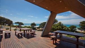 a wooden deck with picnic tables and a view of the ocean at Iconic Luxury & Ocean Views in Apollo Bay