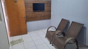two chairs in a room with a door and a television at Apartamento no Centro Proximo a Tudo in Barra do Garças